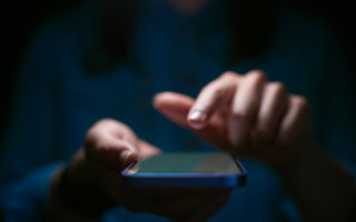 Personen använder en smarttelefon i mörkret