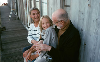 Vanhempi pariskunta istuu lapsen kanssa terassilla